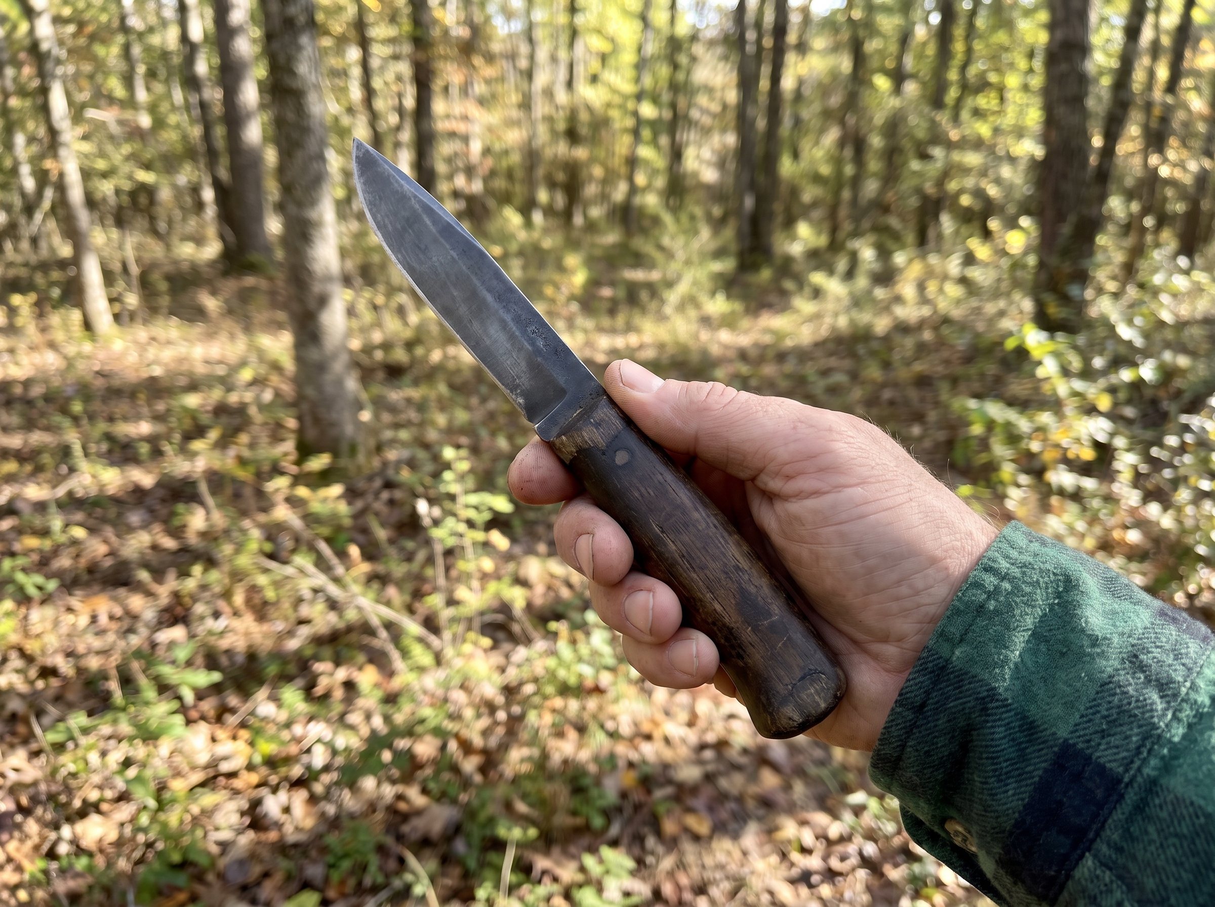Couteau de chasse à lame fixe tenu en main en forêt